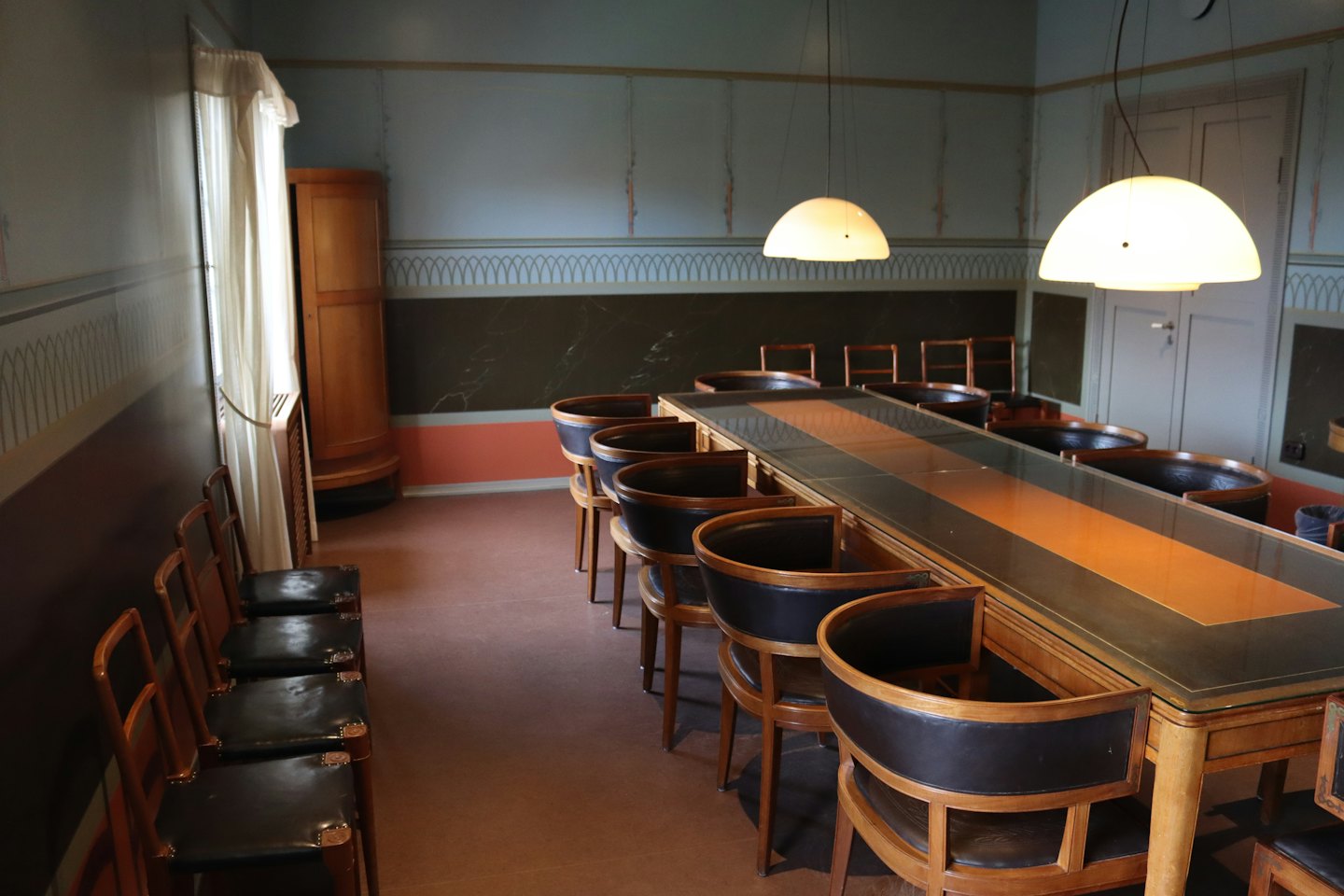 Conference room with a long table and hanging dome lights.